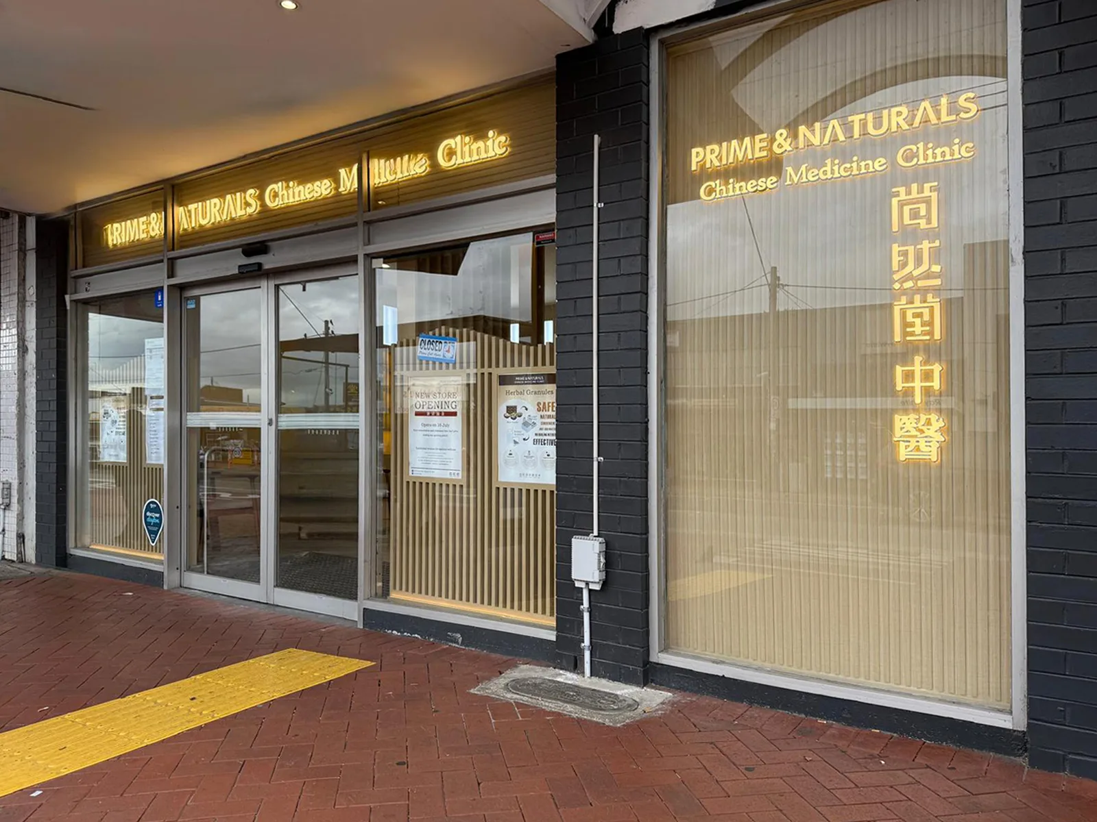 Prime & Naturals shopfront viewed from the corner pillar — bilingual clinic signage