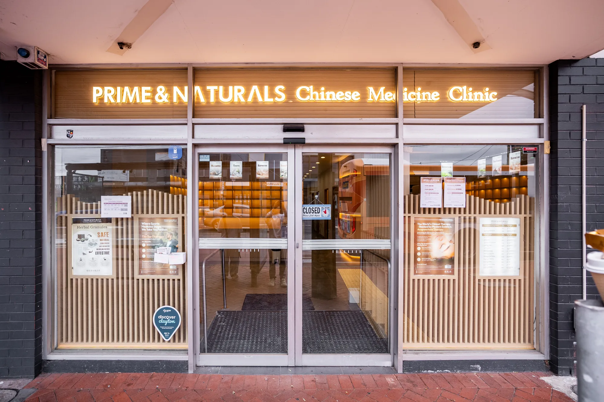 Prime & Naturals shopfront by day — bilingual Chinese and English wordmark above the clinic entrance