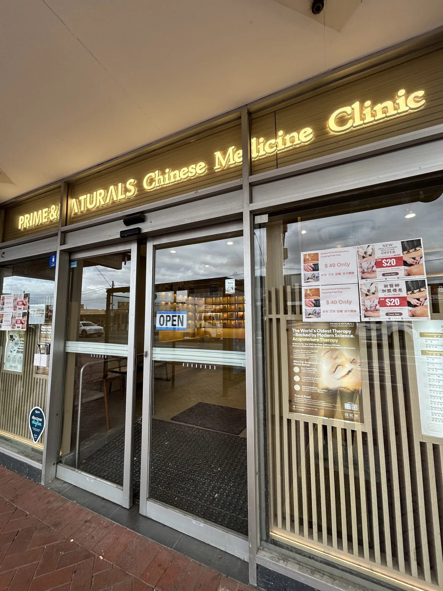 Prime and Naturals shopfront at dusk with glowing gold wordmark and OPEN sign