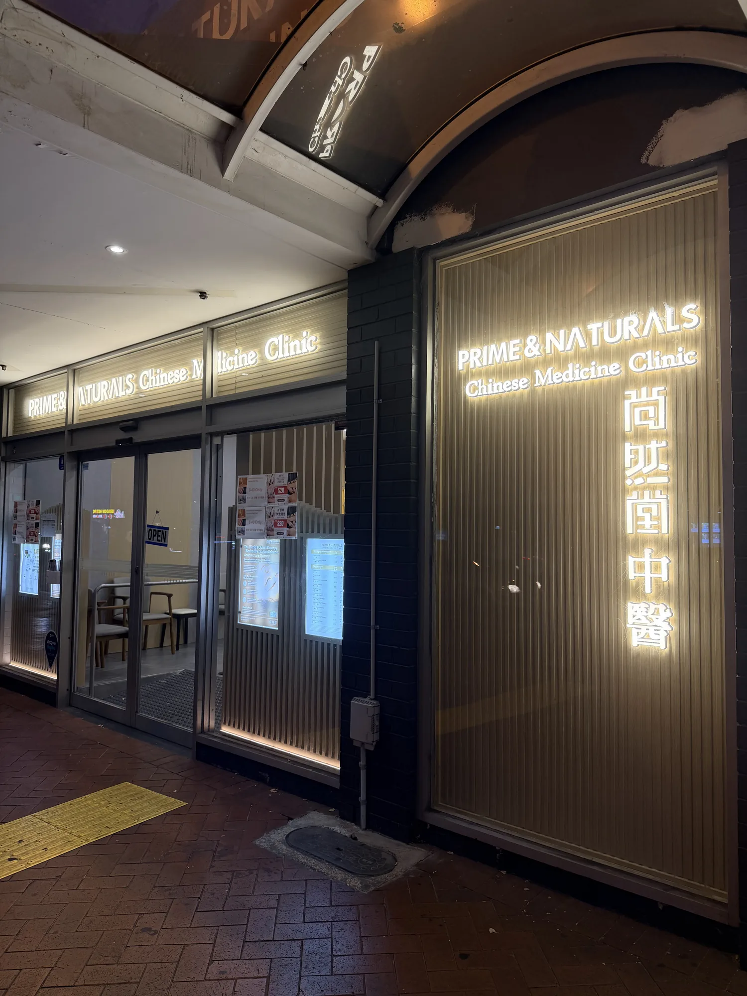 Prime and Naturals shopfront at night with glowing gold wordmark and vertical Chinese characters