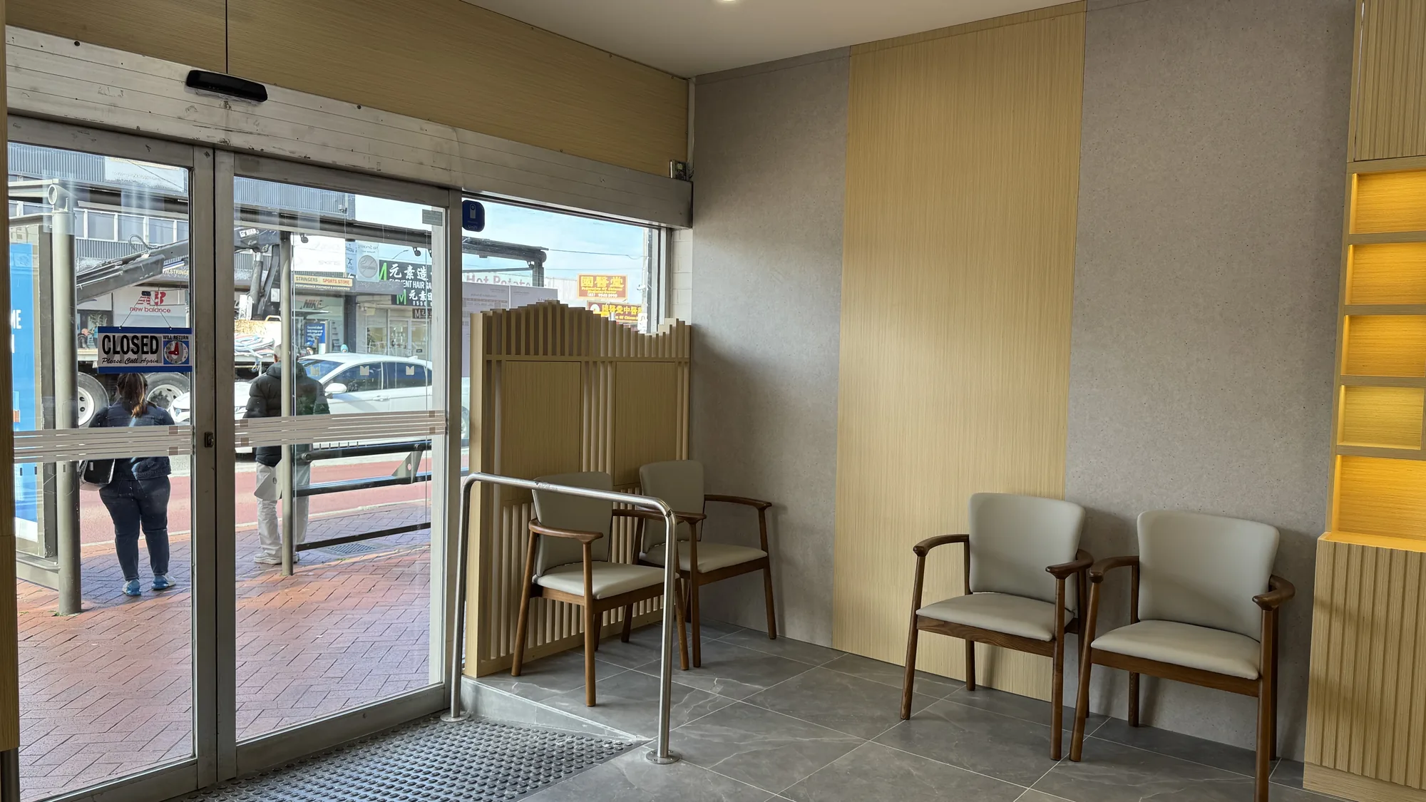Clinic waiting area — pale leather chairs beside oak slat screen